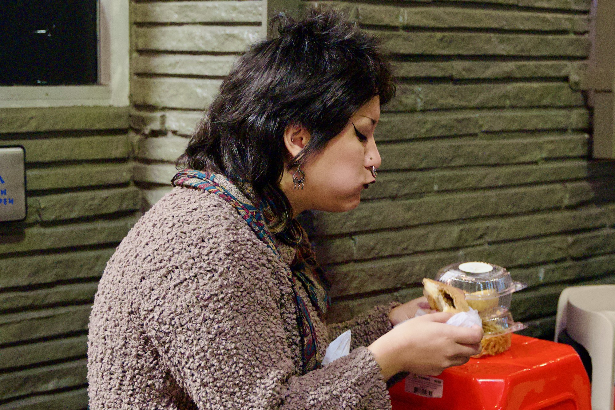 A woman eating beside a storefront