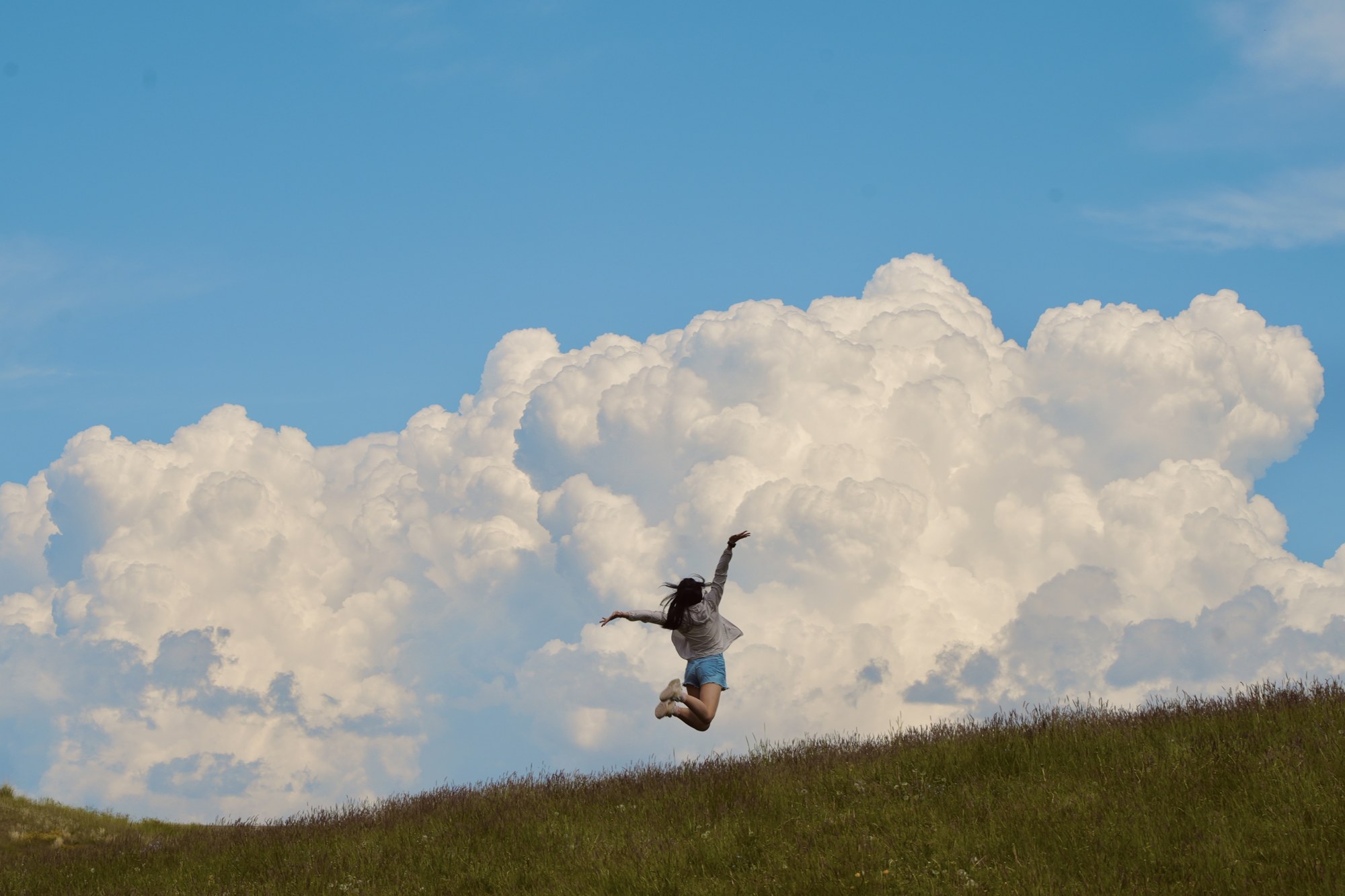 A person jumping against a cloud-filled sky