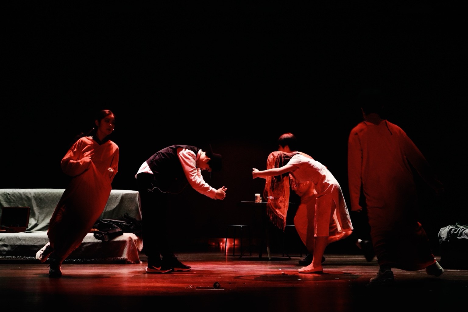 Actors performing under red stage lighting