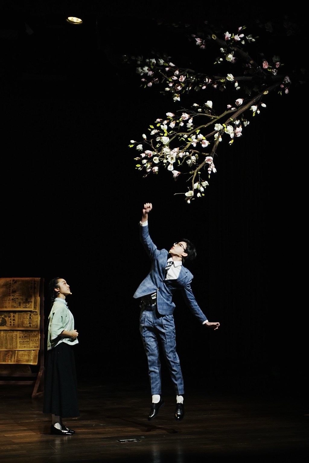 An actor leaping beneath flowering branches onstage