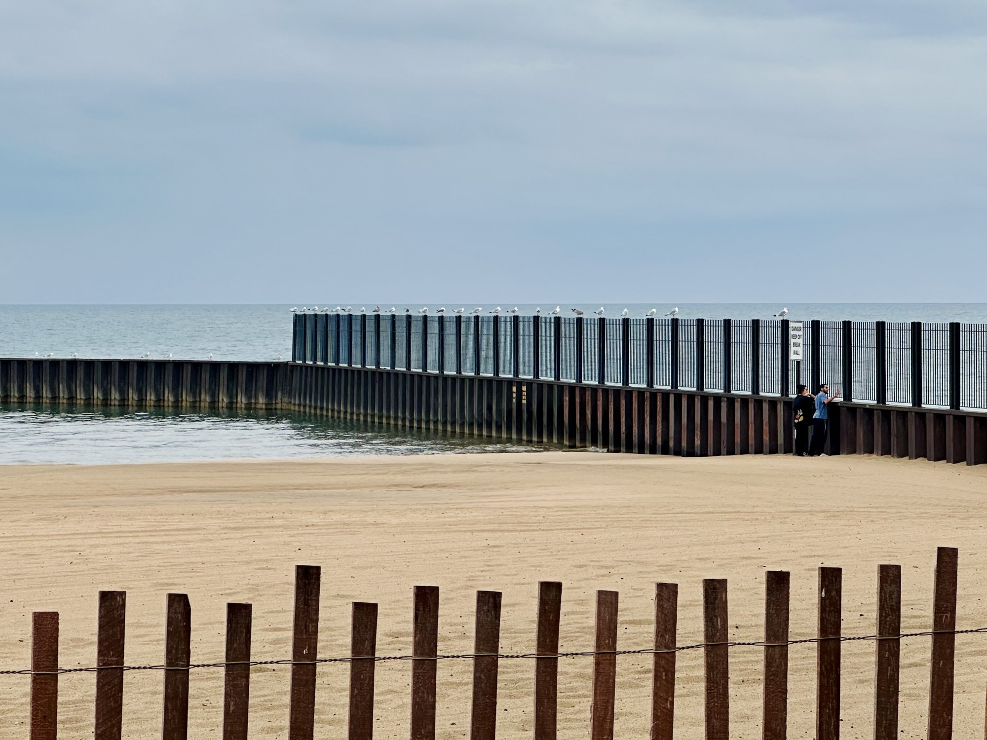 A sandy beach framed by rows of vertical posts
