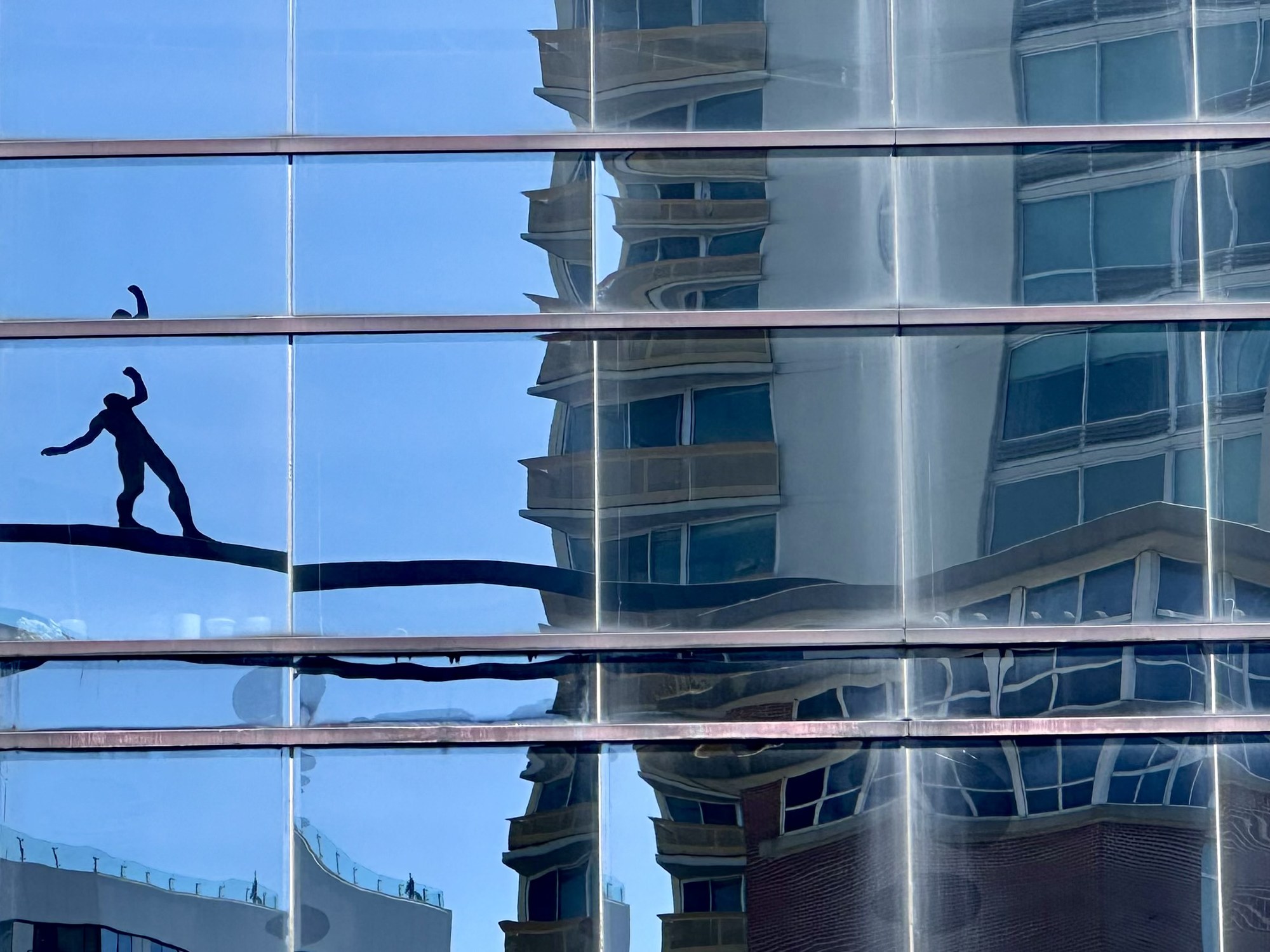 A silhouetted figure and buildings reflected in glass