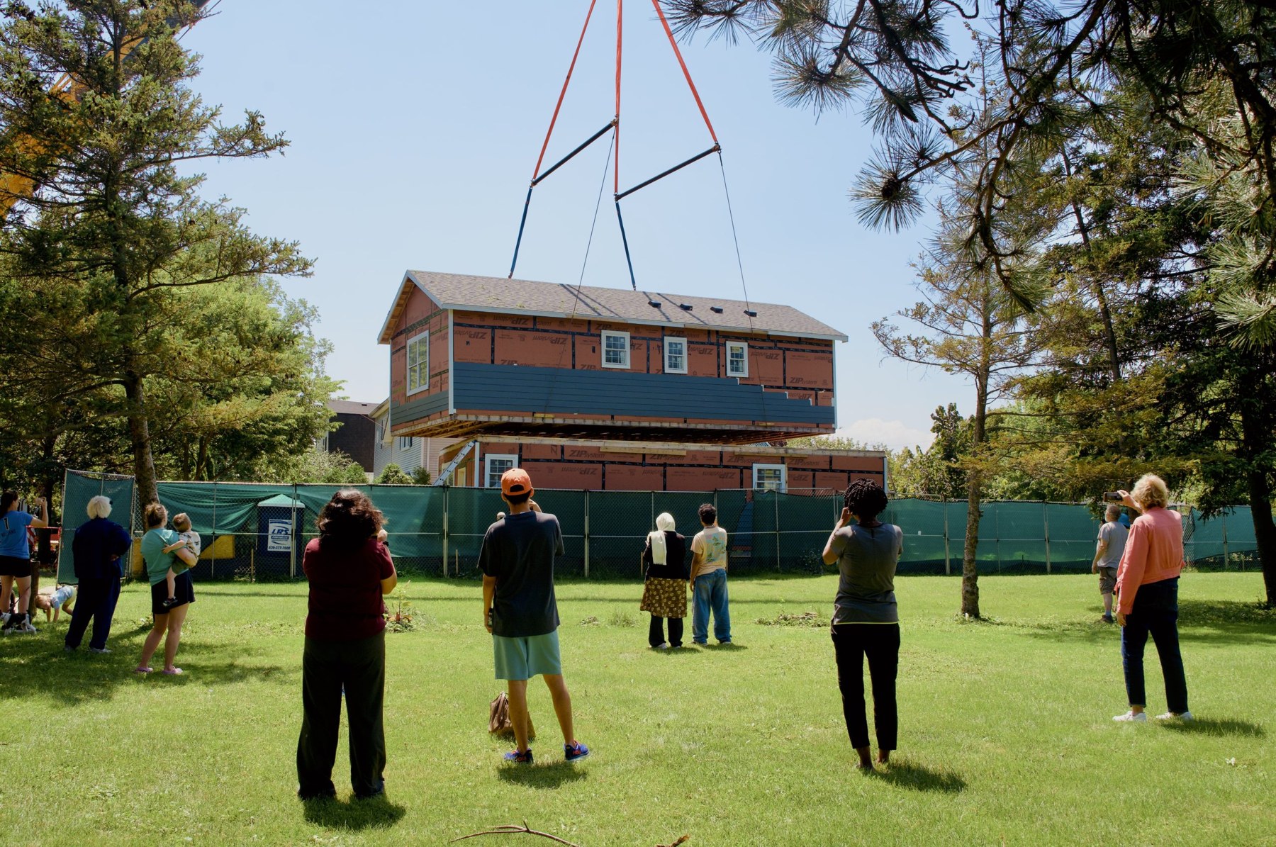 People watch on as the second-story model is set upon the first by a crane.