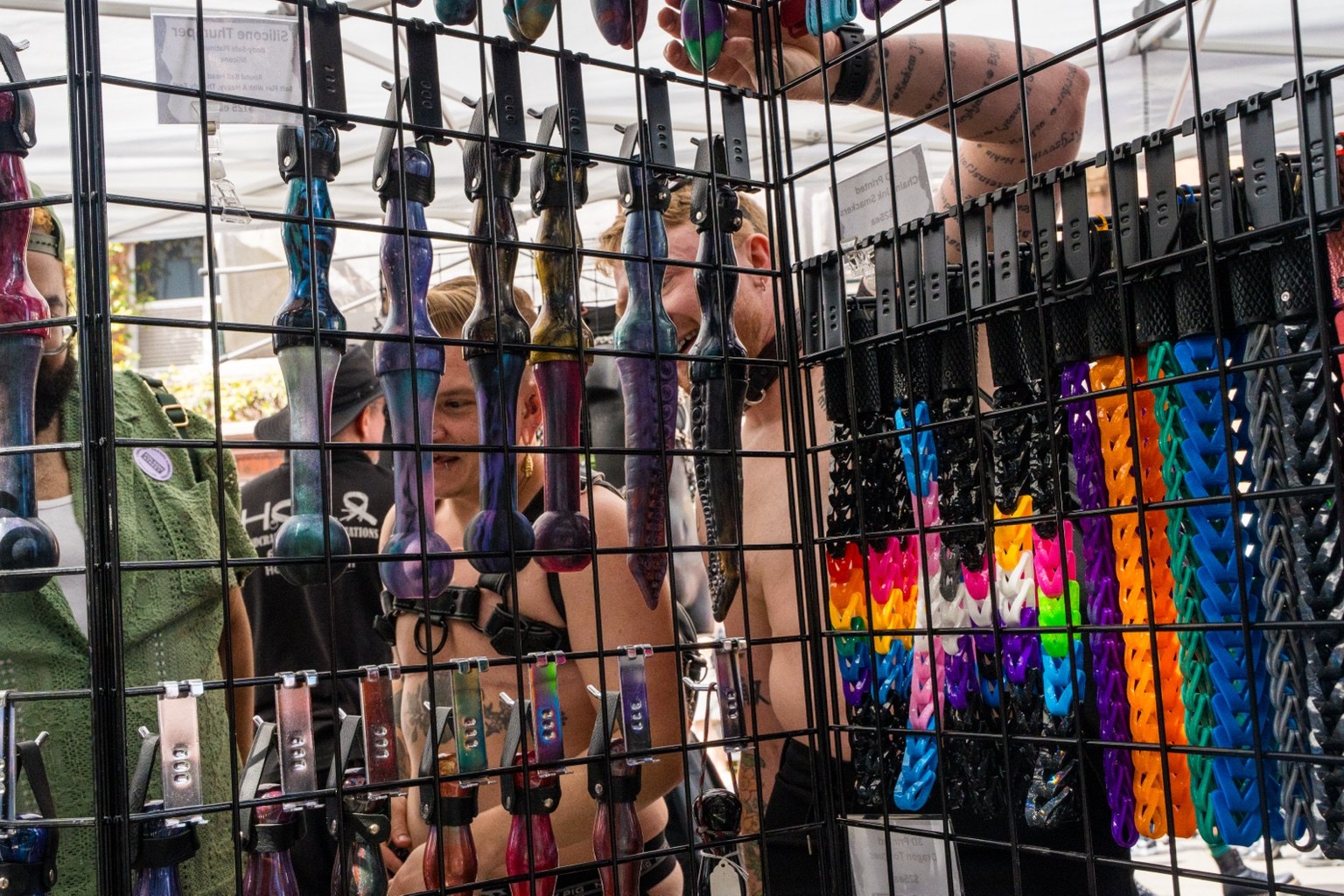 Fairgoers browse a vendor’s stall behind a metal display grid at the 43rd annual Folsom Street Fair in San Francisco on Sept. 27, 2026.