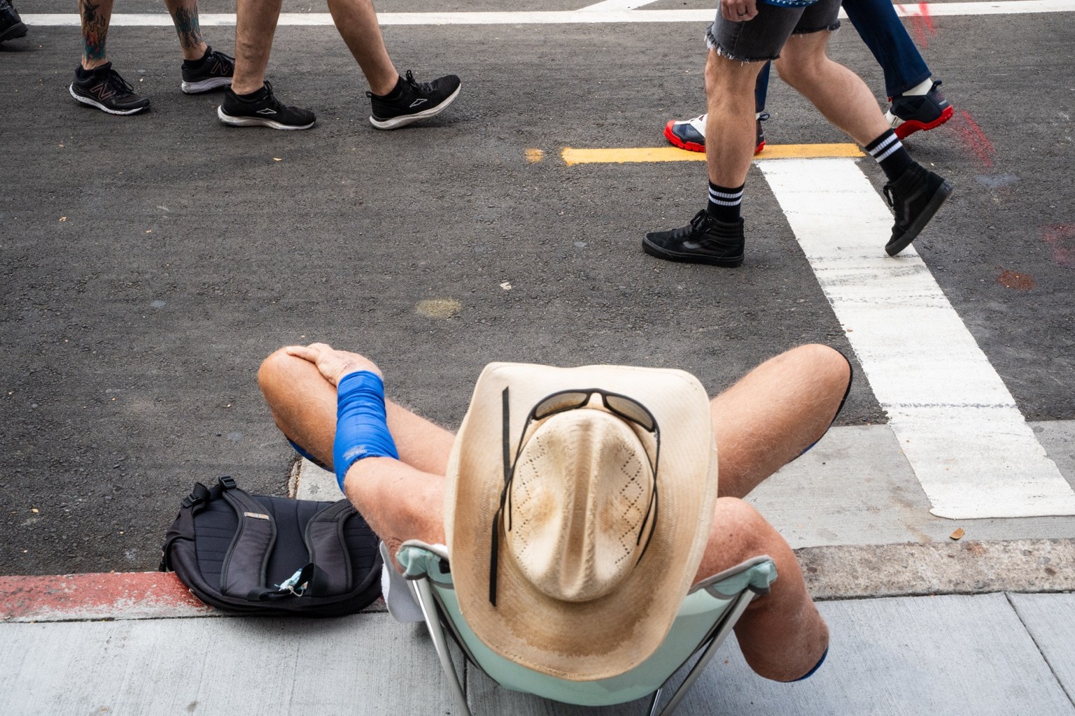 A fairgoer wearing a cowboy hat rests beside the street at the 43rd annual Folsom Street Fair in San Francisco on Sept. 27, 2026.