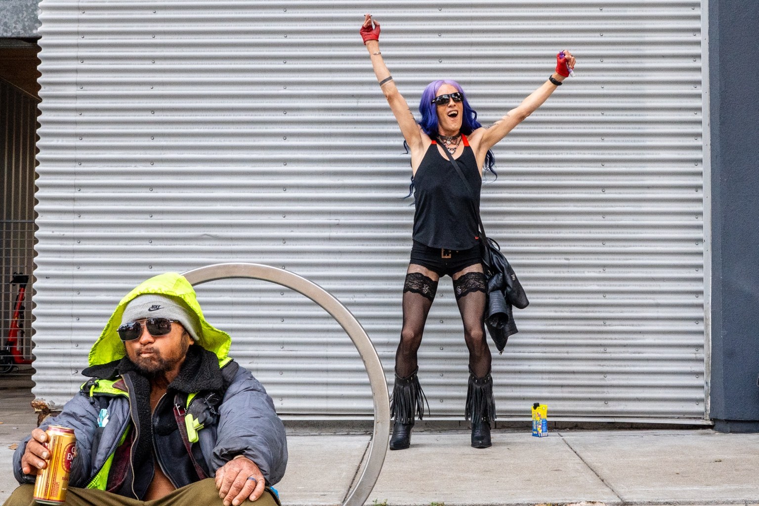 A fairgoer raises both arms beside a corrugated metal wall at the 43rd annual Folsom Street Fair in San Francisco on Sept. 27, 2026.