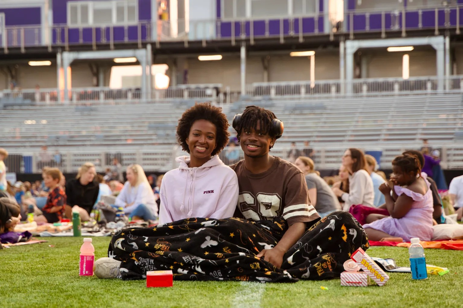 Two people seated together on a lawn.