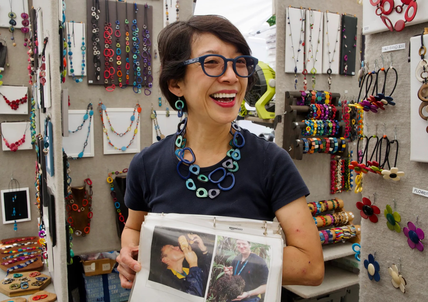 A smiling person holding a photograph in a shop.