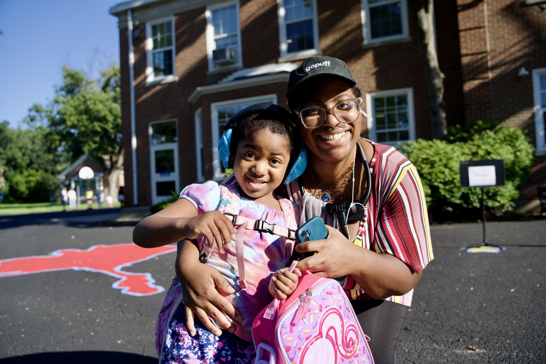 An adult and child smile together outdoors.