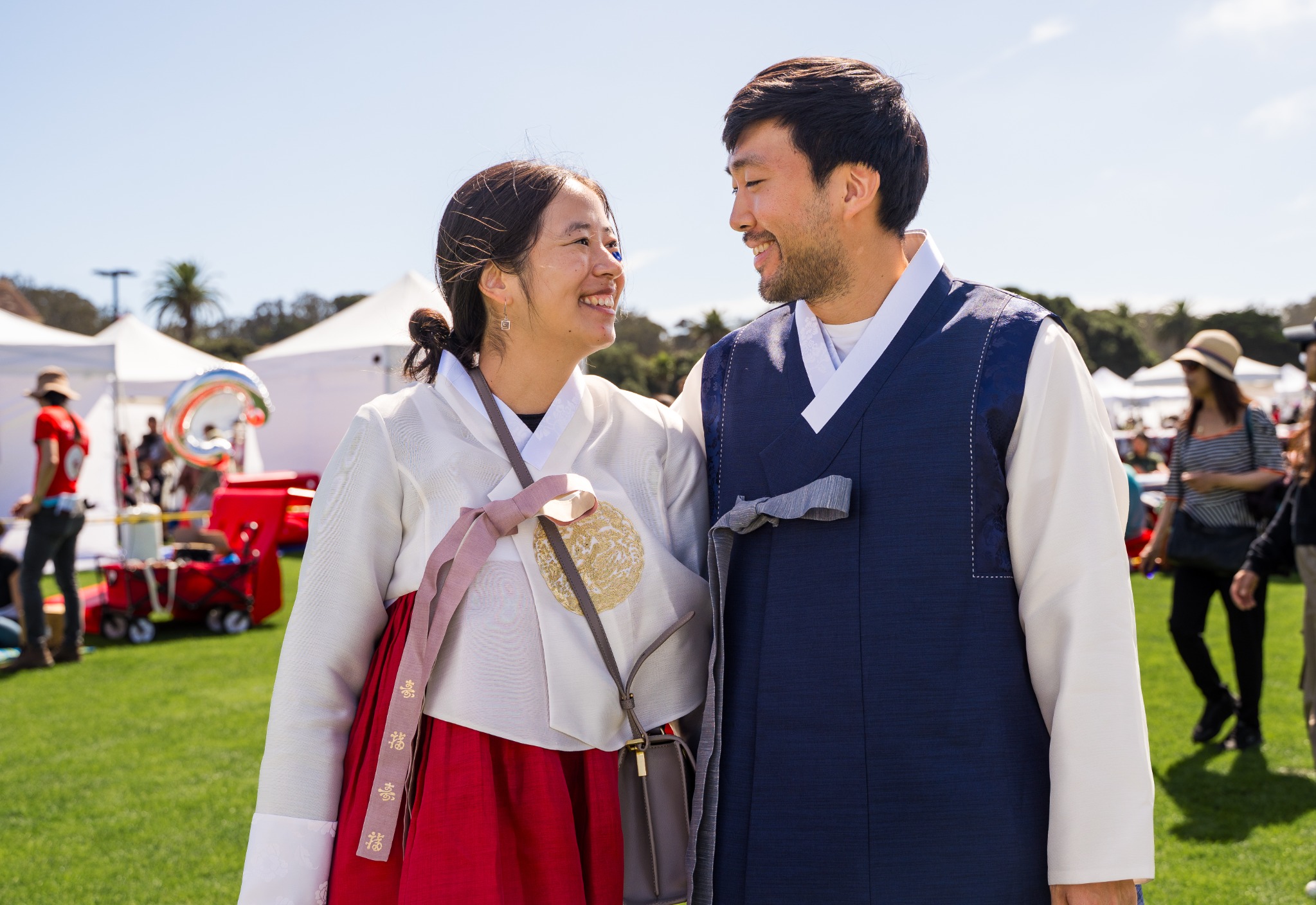 Two people wearing hanbok look at one another.